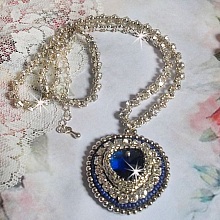 Collier Saphir Bleu brod&eacute; &agrave; l'aiguille avec un c&oelig;ur en cristal de Swarovski, rocailles argent&eacute;es Miyuki, strass, un fermoir et une cha&icirc;nette d'extension en argent 925/1000. Un voyage si lointain.